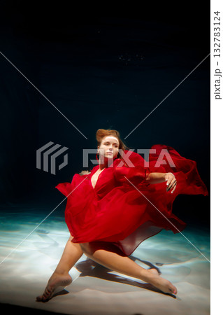 Underwater scene of woman in vibrant dress leaping energetically 132783124