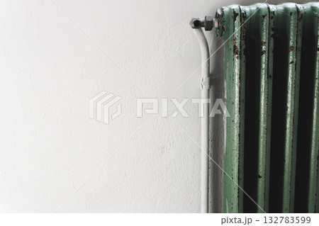 Old green radiator against white wall concept of home heating and energy efficiency. 132783599