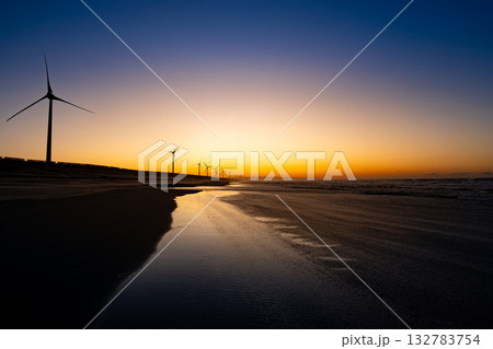朝焼けの海辺に並ぶ風力発電の風車と砂浜の風景 朝焼けの海辺に並ぶ風力発電の風車と砂浜の風景 132783754