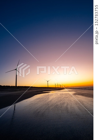 朝焼けの海辺に並ぶ風力発電の風車と砂浜の風景 朝焼けの海辺に並ぶ風力発電の風車と砂浜の風景 132783755