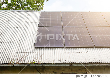 Modern solar panels mounted on an old corrugated metal roof, representing renewable energy 132783900