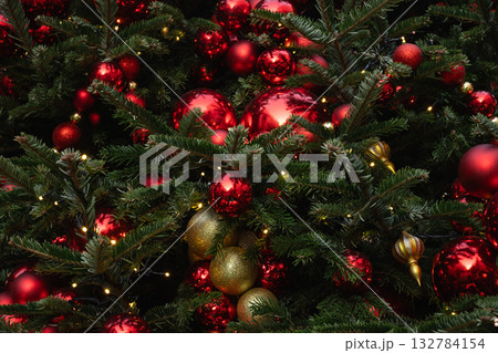 Details decorated Christmas tree with red, golden baubles and garland. Xmas card and pattern. Close up. Winter. Outdoor. Details decorated Christmas tree with red, golden baubles and garland. Xmas card and pattern. Close up. Winter. Outdoor. 132784154