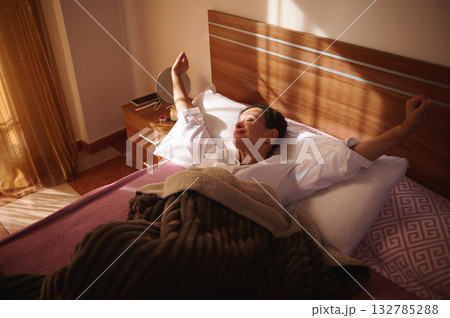 Relaxed Woman Stretching in Bed at Sunrise in a Cozy Bedroom After Morning Wakeup Relaxed Woman Stretching in Bed at Sunrise in a Cozy Bedroom After Morning Wakeup 132785288