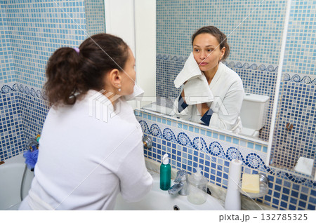 Woman In Bathrobe Looking At Mirror In Blue Mosaic Bathroom 132785325
