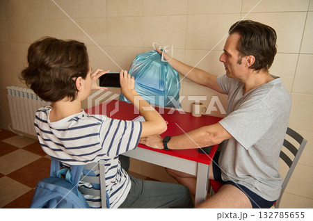 Father And Son Photograph Blue Grocery Bag At Red Table In Kitchen 132785655