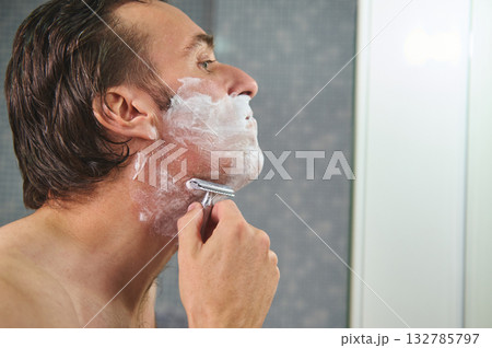 Man Shaving in Bathroom With Foam and Razor - Close Profile View 132785797