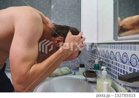 Man Washing Hair At Bathroom Sink With Mosaic Blue Tile Wall And Mirror Man Washing Hair At Bathroom Sink With Mosaic Blue Tile Wall And Mirror 132785813