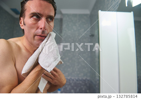 Close-Up Of Man Wiping Face With Towel In Bathroom Mirror 132785814