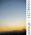 夕暮れの空を飛ぶ飛行機 132786004