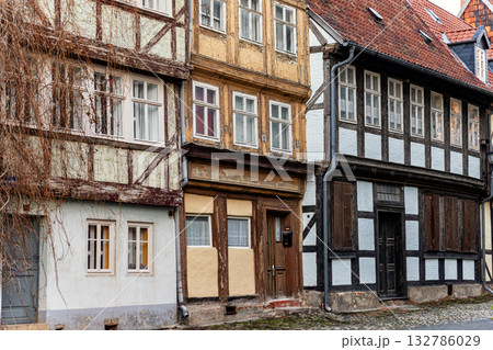 Aged timber-frame houses with peeling paint and faded colors stand close along a narrow cobblestone street. Their weathered surfaces and rustic details evoke nostalgia and charm of old European towns 132786029