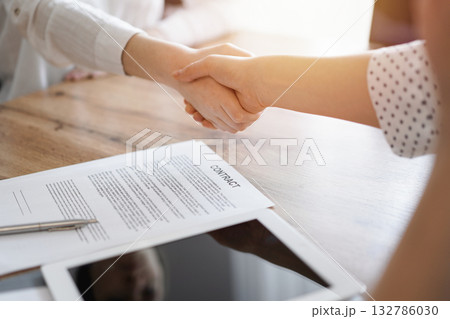 Business people shaking hands above contract papers just signed on the wooden table, close up. Lawyers at meeting. Teamwork, partnership, success concept Business people shaking hands above contract papers just signed on the wooden table, close up. Lawyers at meeting. Teamwork, partnership, success concept 132786030