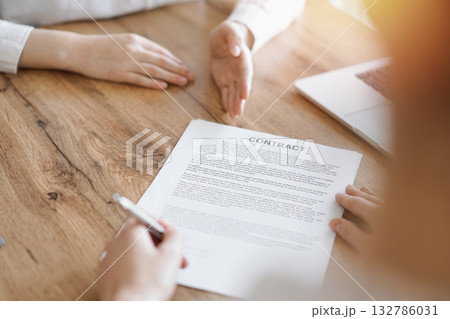 Business people signing contract papers while sitting at the wooden table in office, closeup. Partners or lawyers working together at meeting. Teamwork, partnership, success concept 132786031