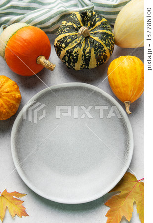 Empty plate surrounded by autumn gourds and leaves Empty plate surrounded by autumn gourds and leaves 132786100