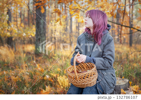 Young girl holding mushroom basket in autumn forest Young girl holding mushroom basket in autumn forest 132786107