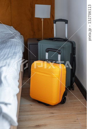 Luggage standing beside bed in modern hotel room 132786113