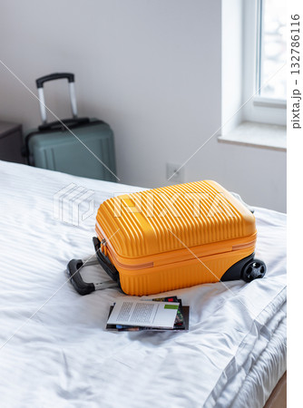 Orange suitcase on hotel bed welcoming travelers arrival Orange suitcase on hotel bed welcoming travelers arrival 132786116