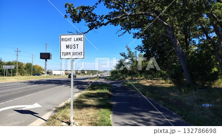 An American highway with a sign indicating movement and a right turn, an empty highway during the day with information signs and an electronic board, road markings and signs indicating the direction 132786698