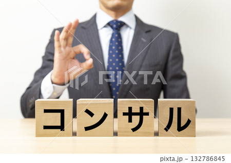 「コンサル」と書かれたブロックとOKポーズをするビジネスマン 「コンサル」と書かれたブロックとOKポーズをするビジネスマン 132786845