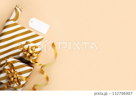 Gift wrapping items. White and gold striped paper, ribbon, gift tag. Copy space Gift wrapping items. White and gold striped paper, ribbon, gift tag. Copy space 132786987