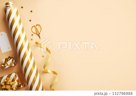 Flat lay of gold and white striped wrapping paper, ribbon, scissors, and small gift boxes. Christmas gift wrapping. Copy space. Flat lay of gold and white striped wrapping paper, ribbon, scissors, and small gift boxes. Christmas gift wrapping. Copy space. 132786988