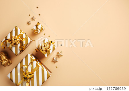 Composition of white and gold striped gifts on a beige background. Space for text, congratulations, wishes. Composition of white and gold striped gifts on a beige background. Space for text, congratulations, wishes. 132786989