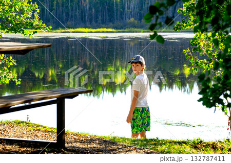 Teen boy at the little forest lake in hot summer day. Teen boy at the little forest lake in hot summer day. 132787411