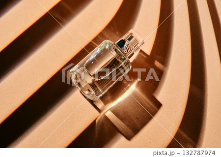 Is the perfume spray bottle lying on a beige background with shadow stripes. Is the perfume spray bottle lying on a beige background with shadow stripes. 132787974
