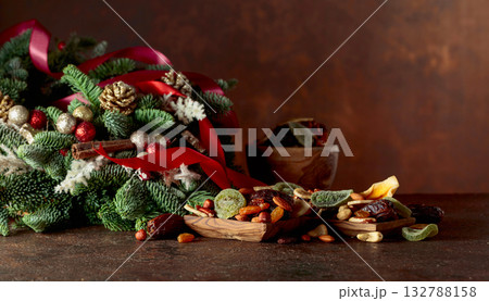 Dried fruits and nuts with Christmas wreath on a brown vintage table. Dried fruits and nuts with Christmas wreath on a brown vintage table. 132788158