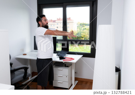 Young caucasian male stretching in home office for a relaxed work environment 132788421