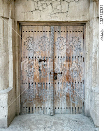 Ornate weathered wooden door with traditional carvings and metal lock on aged stone wall. Historic architecture background.  132788525