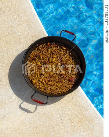 Spanish Paella Beside a Swimming Pool on a Sunny Day 132788531