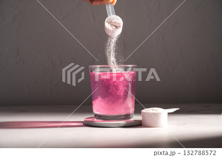 Pouring food supplement powder in glass of water. Collagen, protein powder, vitamins. 132788572