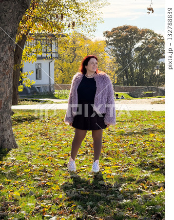 Woman posing near tree surrounded by autumn leaves. Self-expression, inner balance and peaceful connection with nature. Woman posing near tree surrounded by autumn leaves. Self-expression, inner balance and peaceful connection with nature. 132788839