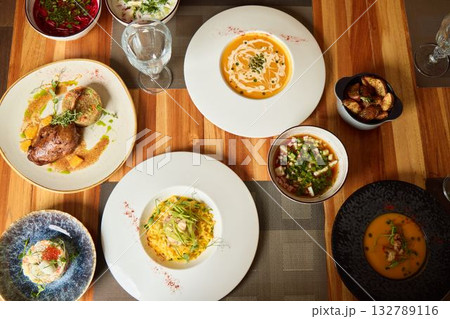 A Variety of Gourmet Dishes Artistically Spread Across a Rustic Wooden Table Setting A Variety of Gourmet Dishes Artistically Spread Across a Rustic Wooden Table Setting 132789116