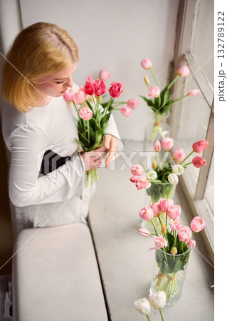 Serene scene of woman appreciating delicate spring blossoms Serene scene of woman appreciating delicate spring blossoms 132789122