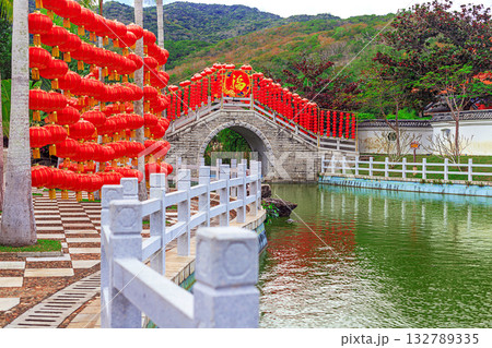A traditional stone bridge with red lanterns in Nianshan Park, Sanya, Hainan, China. 132789335
