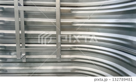 Corrugated metal basement window well with an emergency escape ladder attached to the wall. The curved metal surface and attached safety ladder are evenly lit by natural daylight. Corrugated metal basement window well with an emergency escape ladder attached to the wall. The curved metal surface and attached safety ladder are evenly lit by natural daylight. 132789481