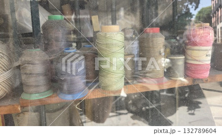 Vintage spool collection in rustic workshop setting for crafting and sewing projects. Fabric store window with skeins of thread 132789604