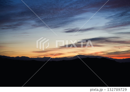 Sunset landscape with colorful sky and mountains in silhouette under evening light and clouds 132789729
