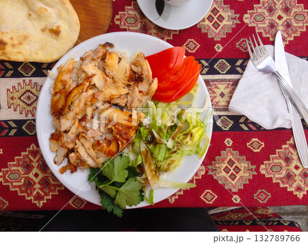 Close-up of grilled chicken and fresh salad served with bread top view. Authentic flavors, color harmony, and simplicity of Turkish street dining. 132789766
