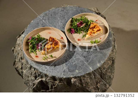 Enjoy a slice of savory quiche with a fresh salad, beautifully served on rustic plates Enjoy a slice of savory quiche with a fresh salad, beautifully served on rustic plates 132791352