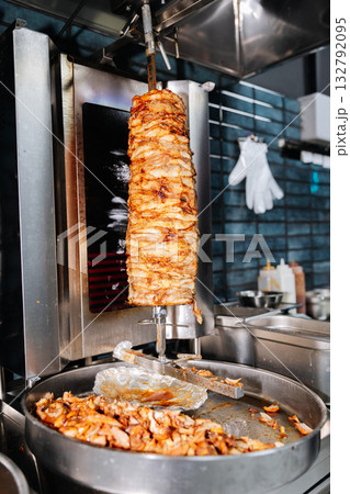 Freshly grilled shawarma meat rotating on vertical spit in modern restaurant kitchen 132792095