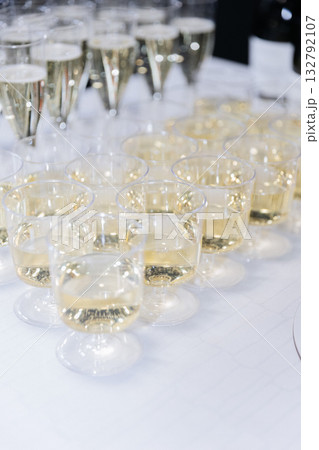 Plastic glasses filled with sparkling wine on white table prepared for festive celebration Plastic glasses filled with sparkling wine on white table prepared for festive celebration 132792107