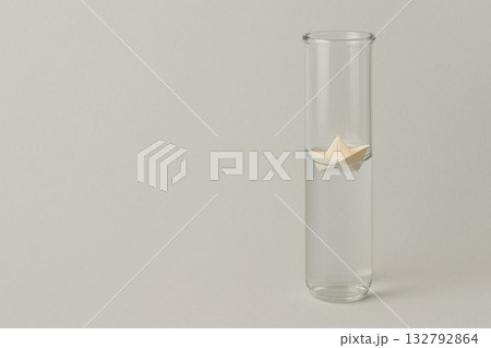 The paper boat floats in a tall glass flask. Space for text. The paper boat floats in a tall glass flask. Space for text. 132792864