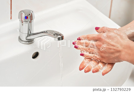 Young woman washing her hands under water tap faucet with soap. Detail on liquid over skin. personal hygiene concept 132793229