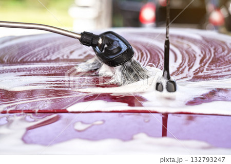 Brush leaving strokes in white shampoo and foam on roof of red car washed in self serve carwash Brush leaving strokes in white shampoo and foam on roof of red car washed in self serve carwash 132793247