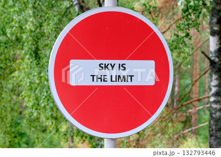 A motivational sign stands on a trail, the red circle reading Sky Is The Limit. It encourages adventure and optimism amidst the greenery of the forest 132793446
