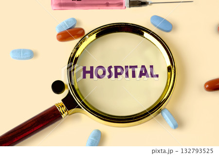 A magnifying glass focuses on the word Hospital. Pills of different colors surround it with a syringe. It looks like someone is trying to understand healthcare 132793525