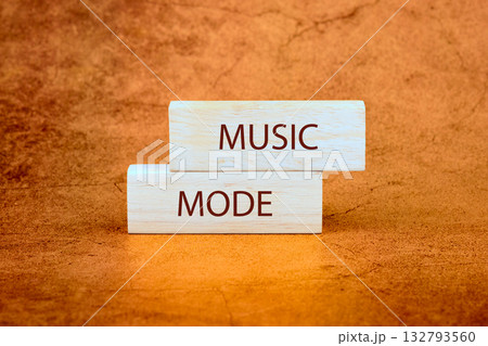 Two wooden blocks are stacked on a textured orange surface. The word MUSIC is printed on the top block, and MODE is printed on the bottom block 132793560