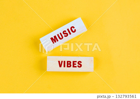 Wooden blocks with the words Music and Vibes in red letters are displayed on a sunny yellow backdrop, radiating a happy and energetic feeling 132793561